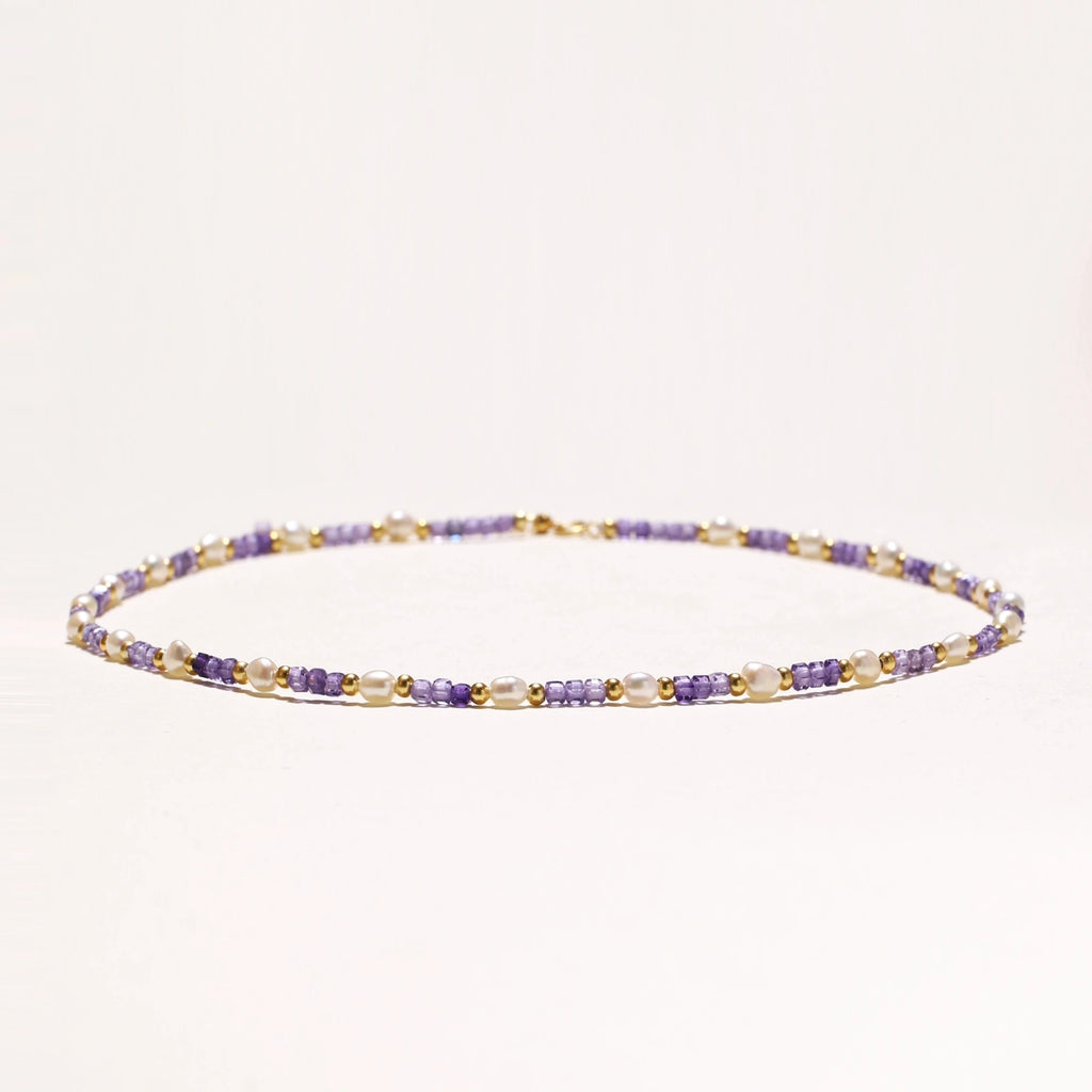 Flat lay of amethyst pearl harmony necklace on neutral background