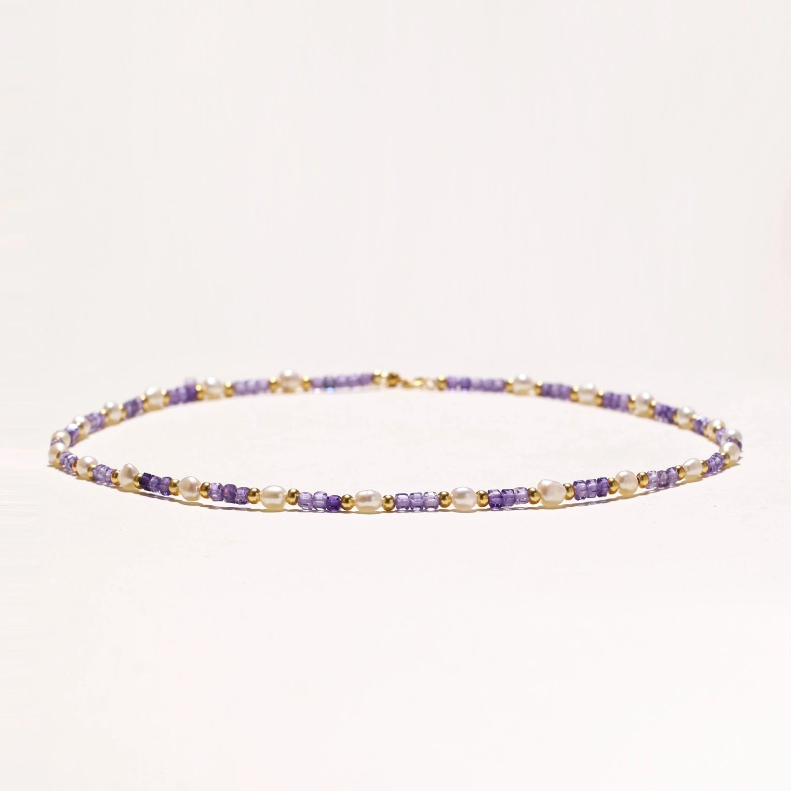 Flat lay of amethyst pearl harmony necklace on neutral background