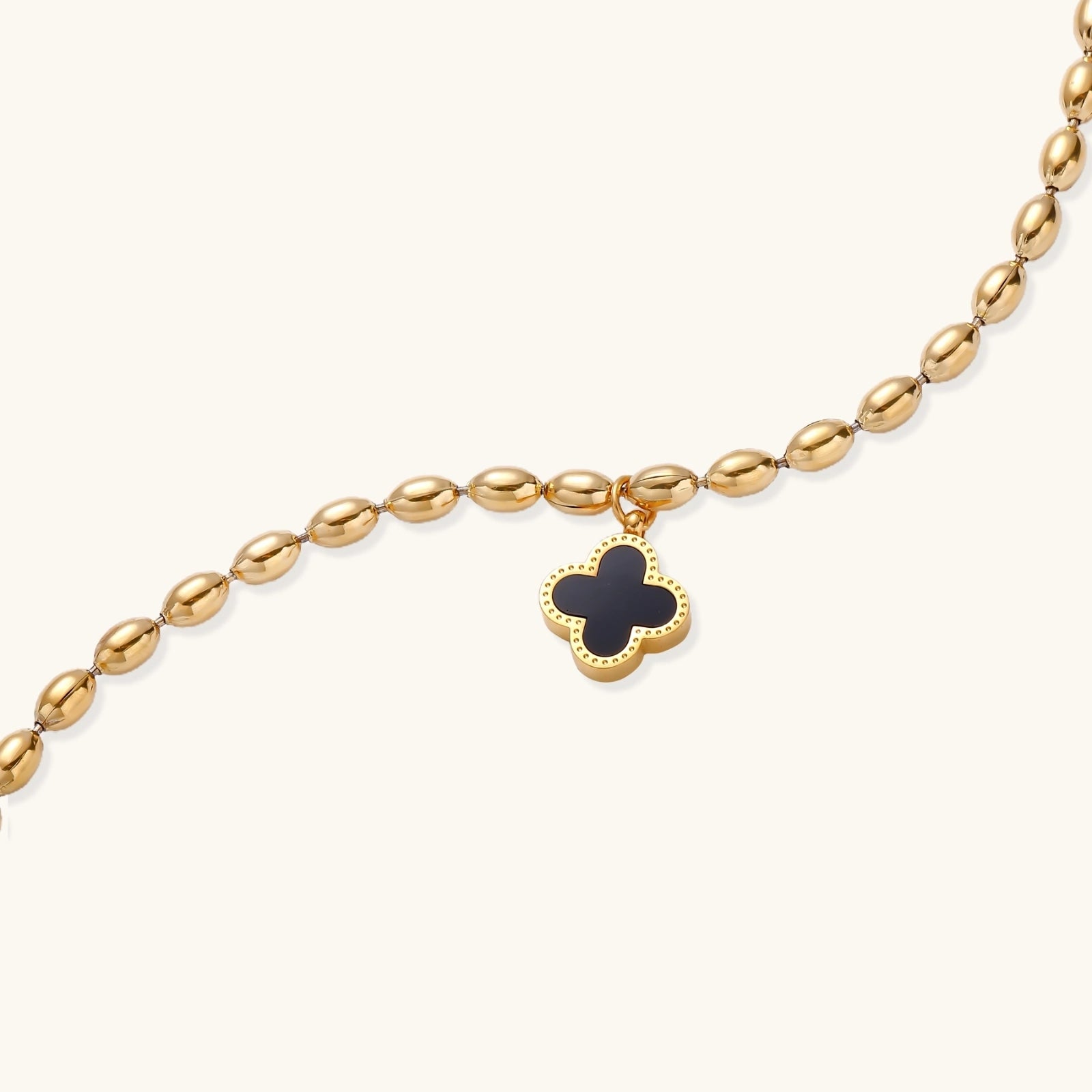 Close-up of gold beaded chain and clover pendant