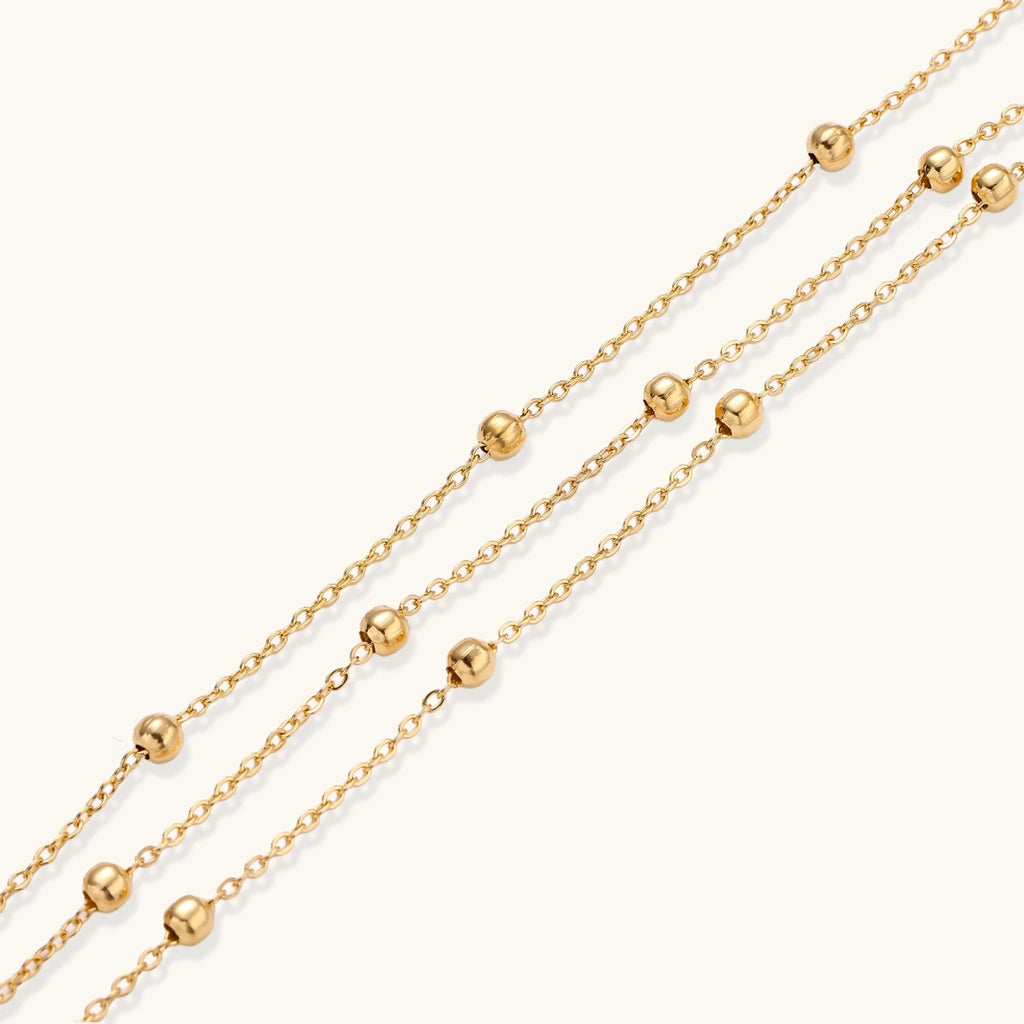 Close-up of triple chain bracelet with small gold sphere accents
