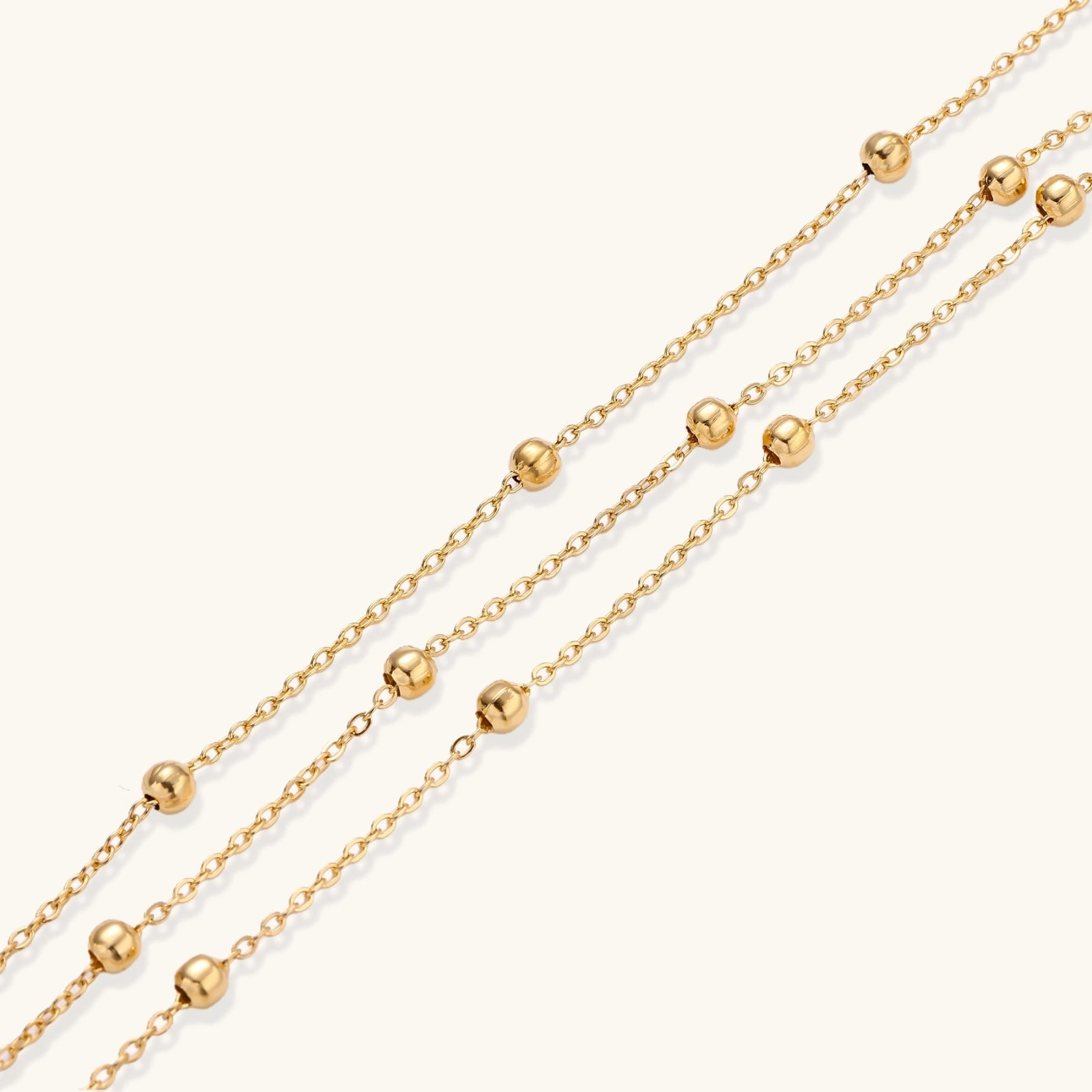 Close-up of triple chain bracelet with small gold sphere accents