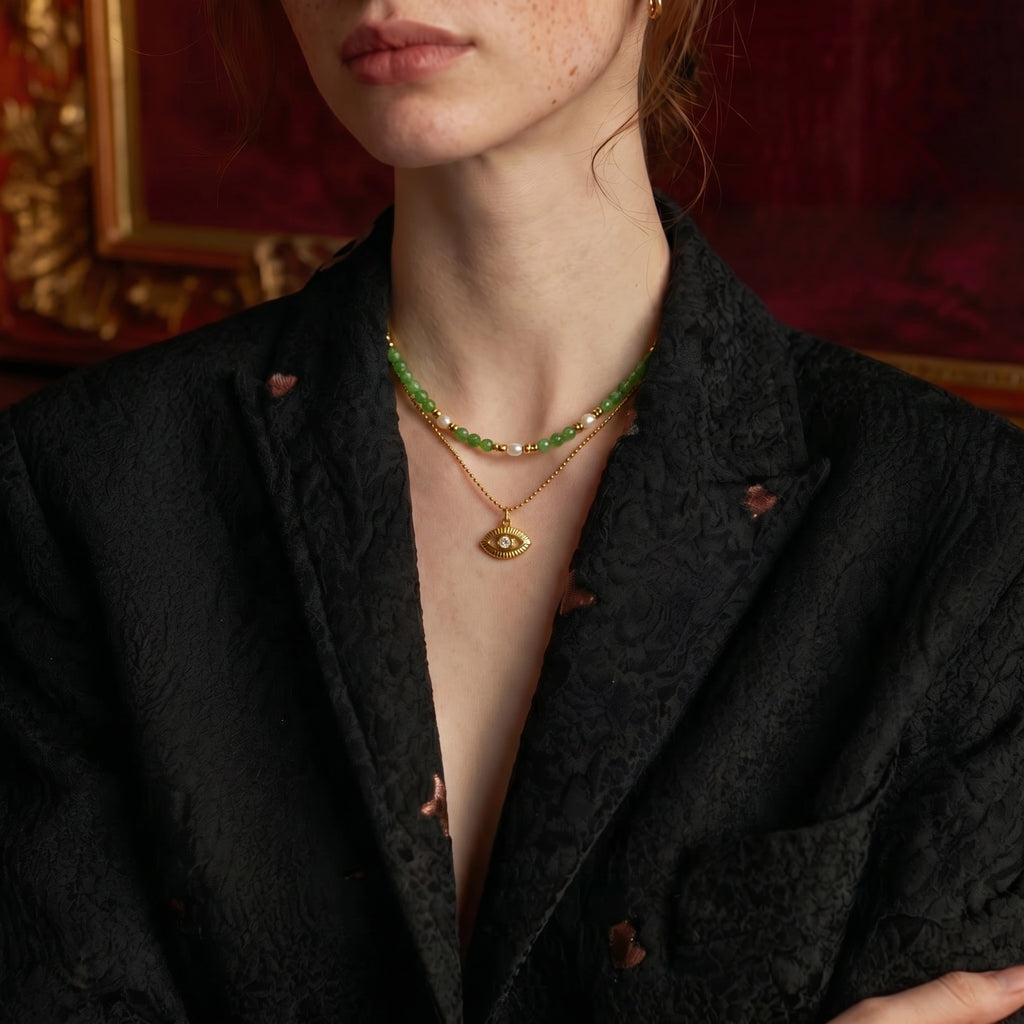 Model close-up wearing layered necklace with gold eye pendant
