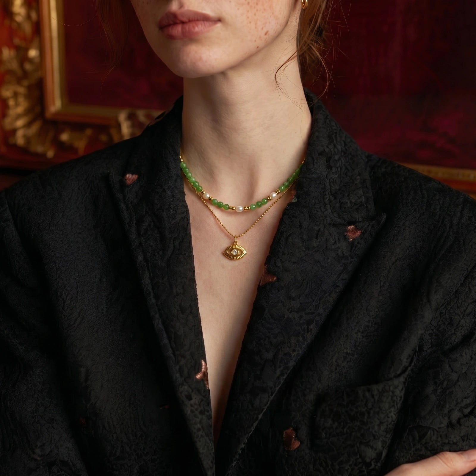 Model close-up wearing layered necklace with gold eye pendant
