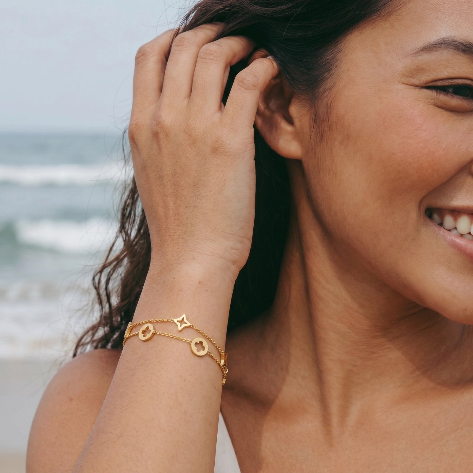 Model wearing GlacierFox Elements star and clover double chain bracelet in gold plated stainless steel