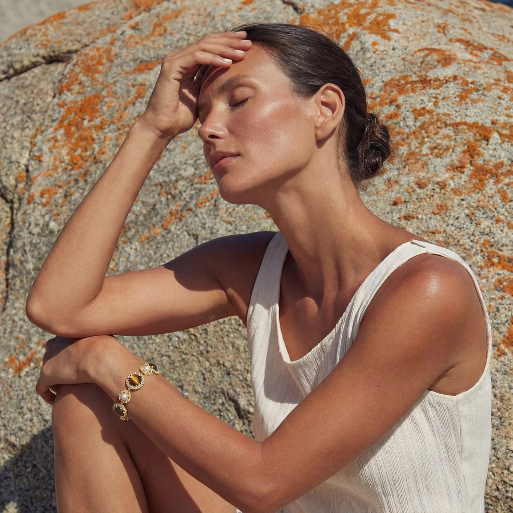 Model wearing GlacierFox Elements tiger’s eye and pearl link bracelet in gold plated 